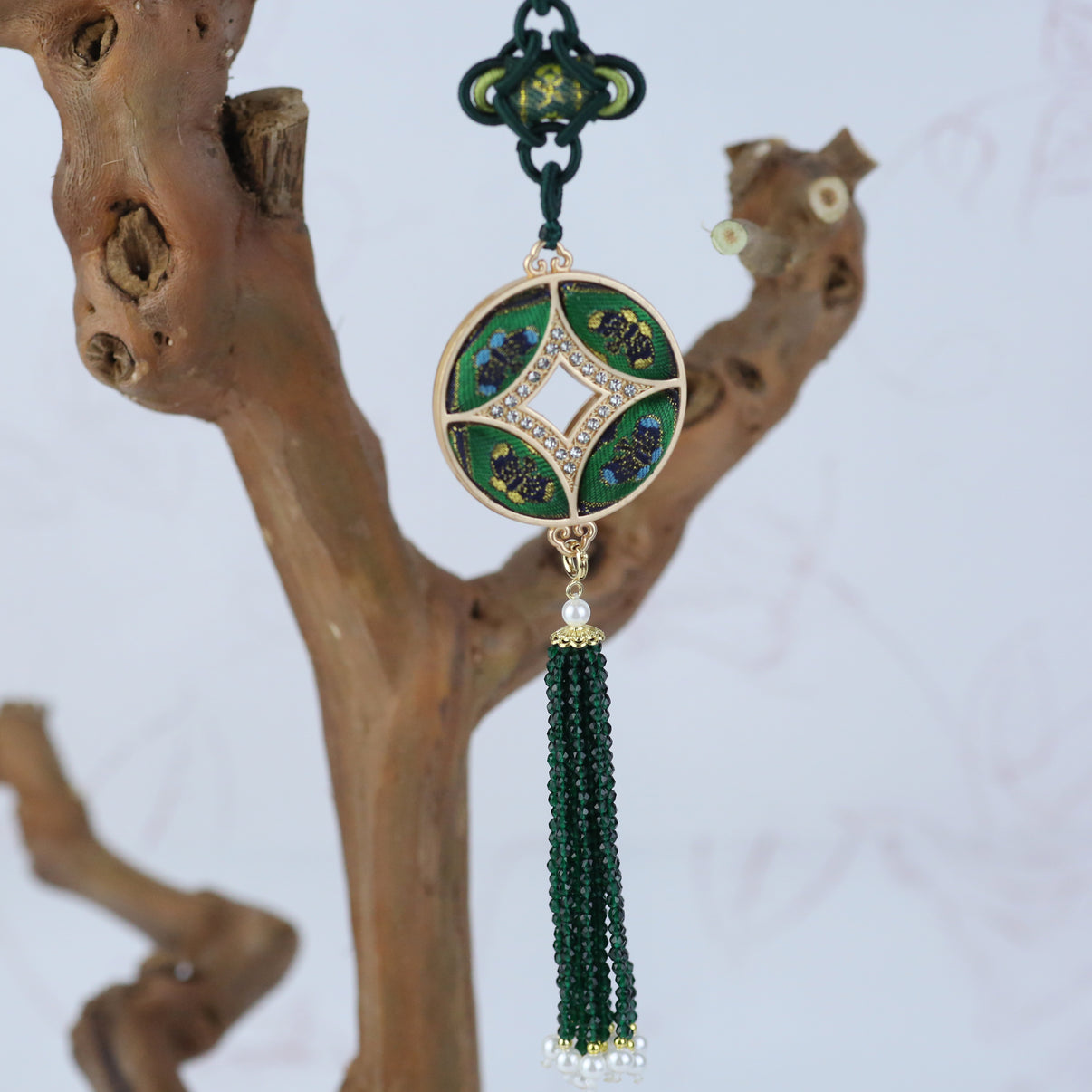 Close-up of the feng shui lucky charm 2026 featuring a double-sided Chinese coin design wrapped in Song brocade with green tassels.